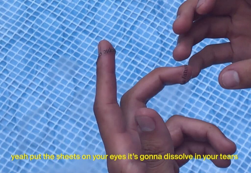 hands wrapped in peeled paper with black words on them above a blue pool